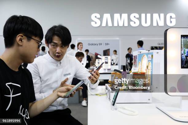 Booth attendant, right, demonstrates a Samsung Electronics Co. Galaxy S9 smartphone to a visitor at the World IT Show 2018 in Seoul, South Korea, on...