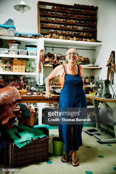 portrait of smiling female shoemaker standing in workshop - large group of craftsman stock-fotos und bilder