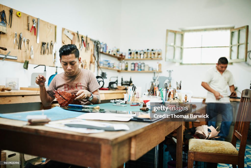 Leatherworkers hand making purses and sandals in workshop