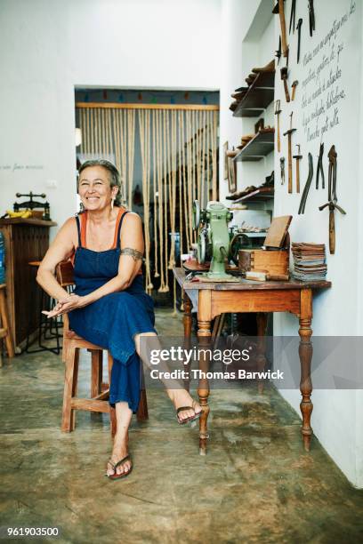 Portrait of smiling female shoemaker sitting at worktable in workshop