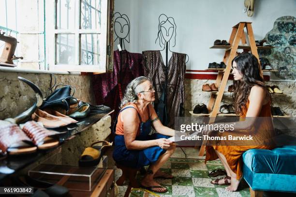 female shoe maker taking custom order from client during fitting in boutique - shoe repair foto e immagini stock