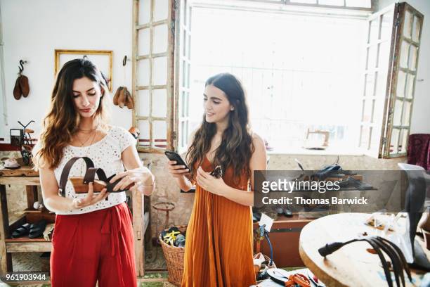 smiling woman using smartphone to take picture of shoe while shopping with friend in boutique - digital footwear stock pictures, royalty-free photos & images