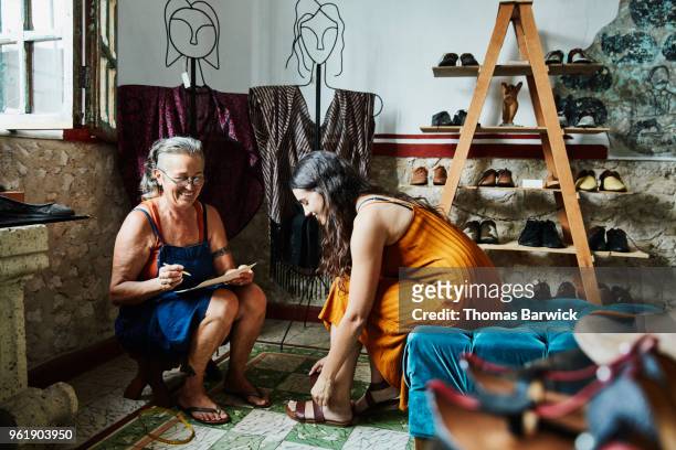 Smiling female shoe maker helping client with custom shoe order in boutique