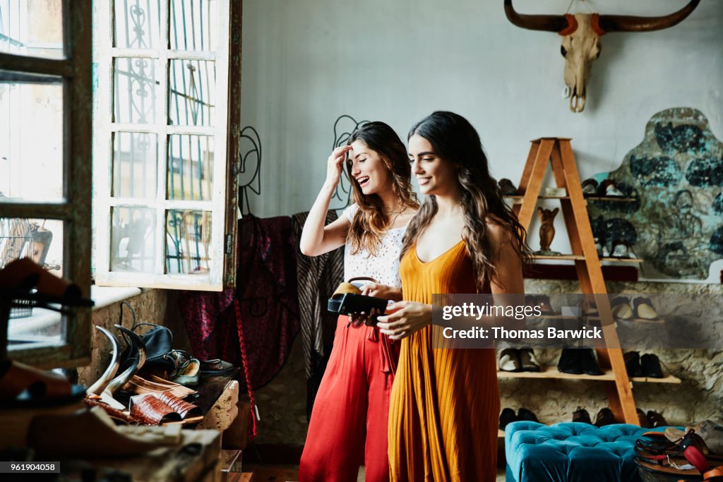 Smiling female friends in discussion while shopping in shoe boutique