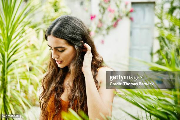 smiling woman standing in courtyard of outdoor spa on sunny afternoon - hand in hair imagens e fotografias de stock