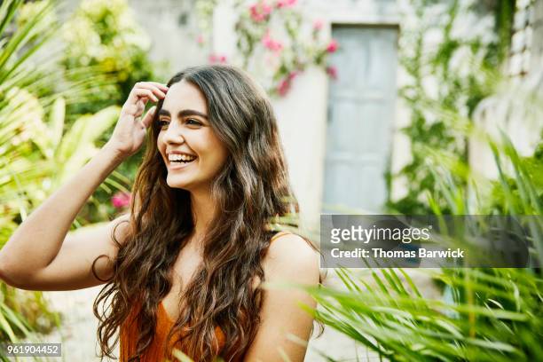 laughing woman standing in courtyard of outdoor spa on sunny afternoon - capelli lunghi foto e immagini stock