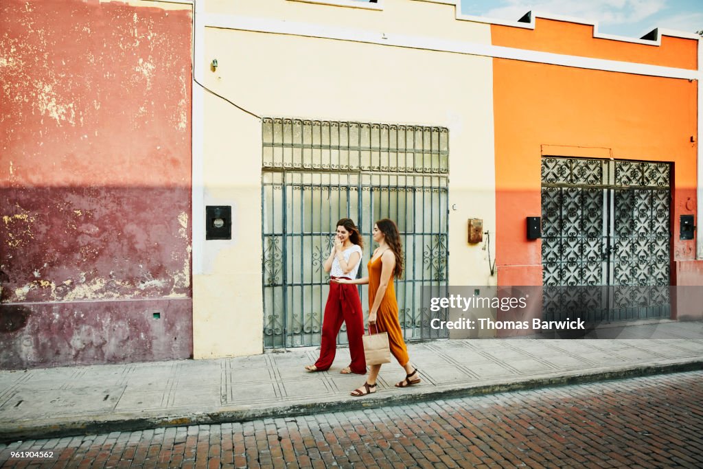 Smiling friends walking through colorful town while shopping during vacation