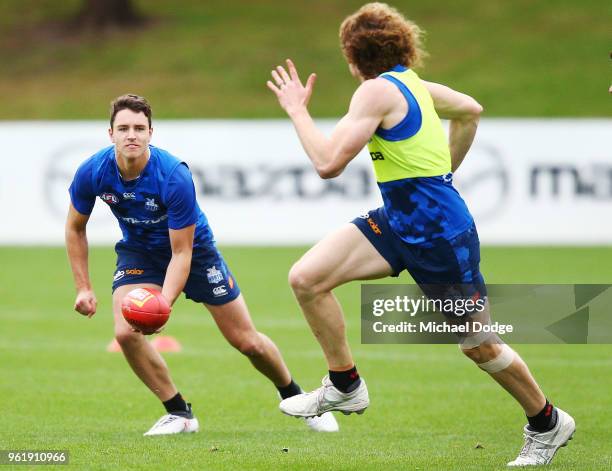 Luke Davies-Uniacke handballs to Ben Brown of the Kangaroos during the North Melbourne Kangaroos AFL training session at Arden Street Ground on May...