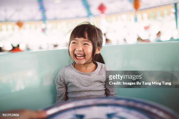 lovely little girl riding on the amusement park ride joyfully. - 遊園地 ストックフォトと画像