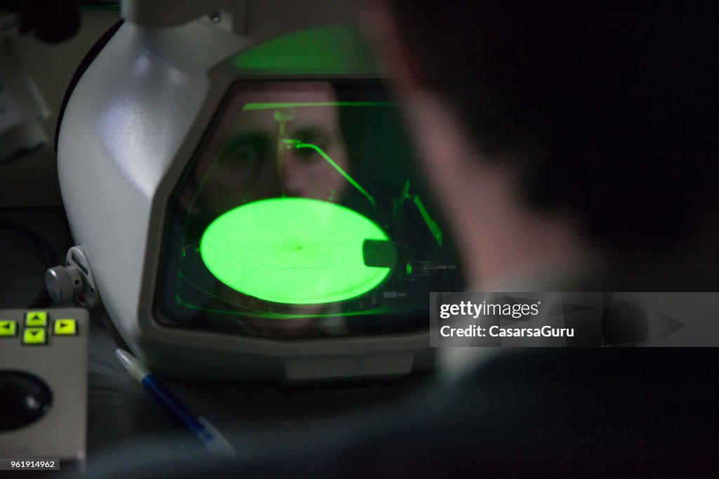Scienziato che guarda al microscopio elettronico ad emissione di campo