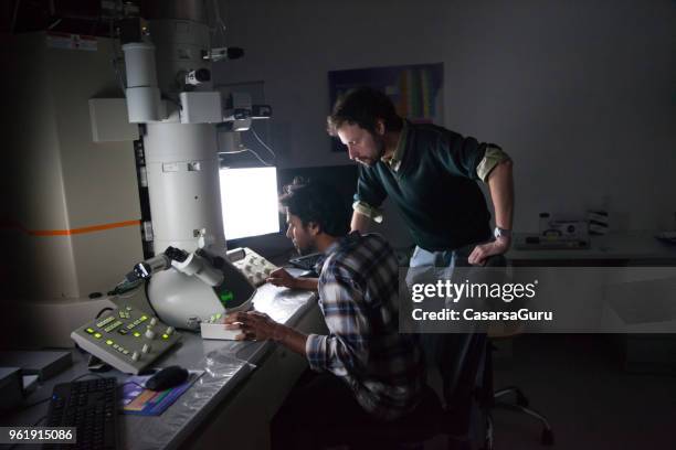 teacher watching student using field emission electron microscope - electron microscope stock pictures, royalty-free photos & images