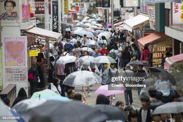 Shoppers with umbrellas walk along Takeshita Street in the Harajuku area of Tokyo, Japan, on Wednesday, May 23, 2018. Japan stocks led declines in...