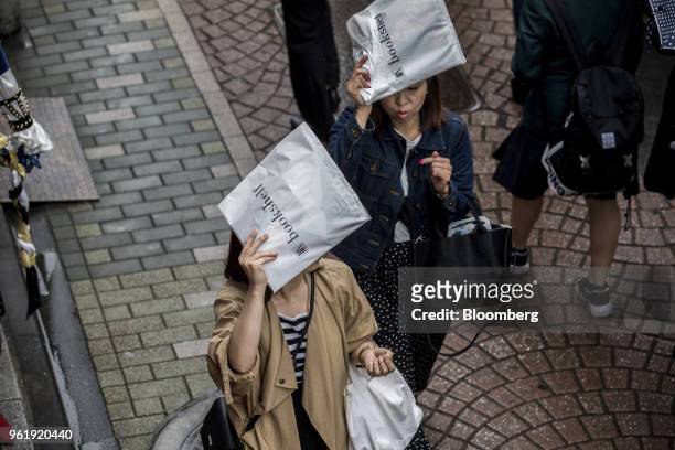 Shoppers shield themselves from the rain as they walk along Takeshita Street in the Harajuku area of Tokyo, Japan, on Wednesday, May 23, 2018. Japan...