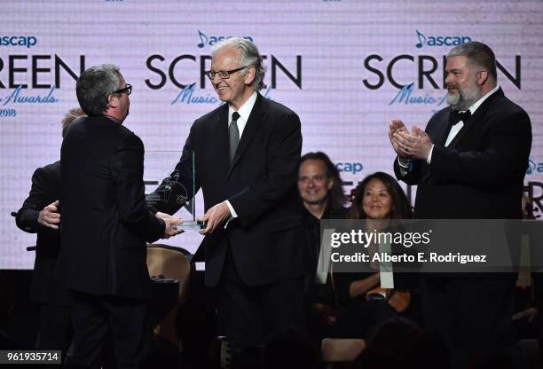 Composer John Powell accepts the Henry Mancini Award from Composer Bruce Broughton and Director Dean DeBlois pose onstage at the 33rd Annual ASCAP...