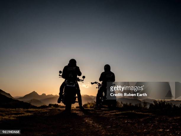 two motorcycles and riders looking at the mountains - motorcycles stockfoto's en -beelden