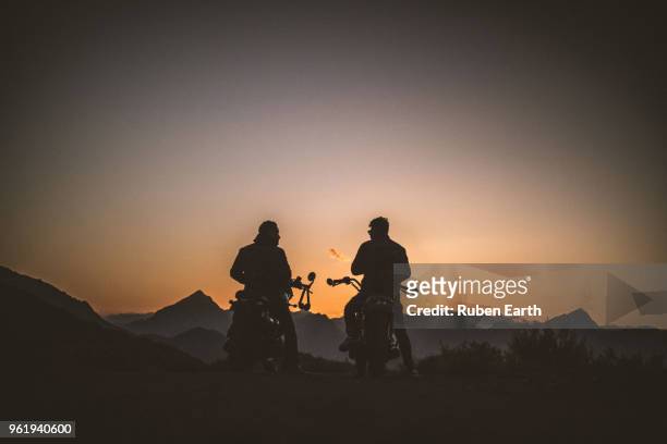 two riders at sunset with their motor bikes - mountain biker stock-fotos und bilder