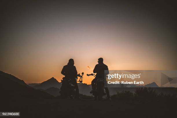 two riders at sunset with their motor bikes - motorcycle rider stock pictures, royalty-free photos & images