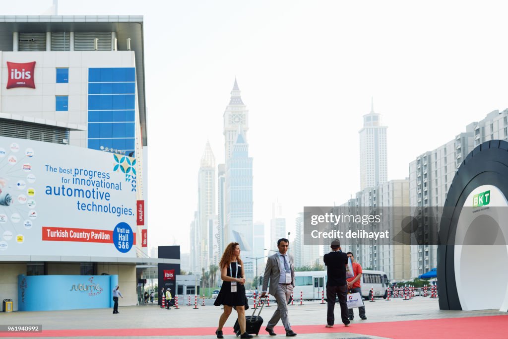 City skyline at the backgrdound and people in front of the Dubai World Trade Centre