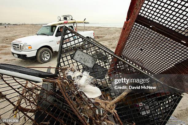 Lifeguard passes a pile of shopping carts gathered by city workers cleaning up trash and debris from the run-off of recent storms near the mouth of...