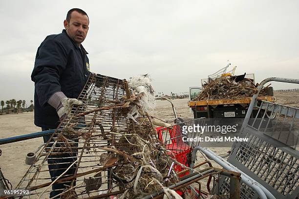 City worker picks up shopping carts that are part of the trash and debris from the run-off of recent storms near the mouth of the San Gabriel River...