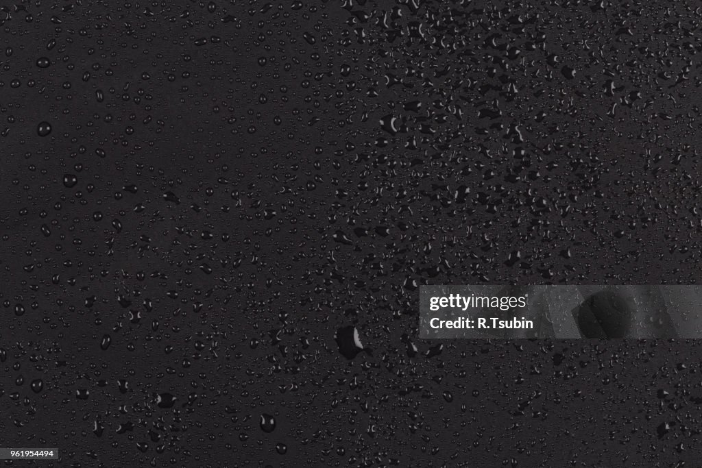 Water drops on dark stone rock surface of basalt or granite