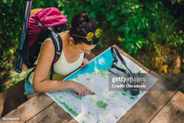 frau reisenden mit rucksack prüft karte wegbeschreibung im wildnisgebiet, echte explorer - wilderness guide stock-fotos und bilder