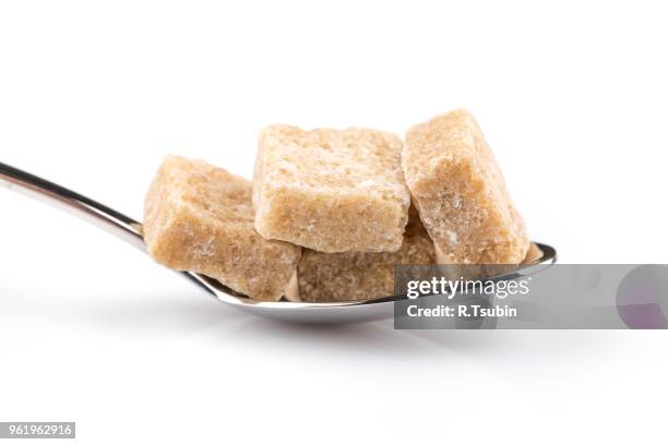 cubes of brown sugar on a metal spoon - jaggery stock pictures, royalty-free photos & images