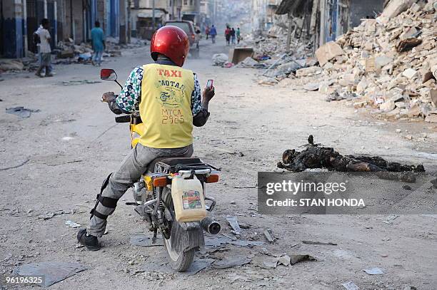 Motorcyclist takes a picture of a burnt corpse burns in downtown Port-au-Prince on January 26, 2010. Quake-hit Haiti will need at least a decade of...