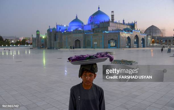 In this photo taken on May 23 an Afghan Bolani vendor looks on as he waits for customers in the courtyard of Hazrat-e Ali shrine, or 'Blue Mosque',...