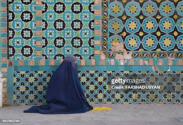 In this photo taken on May 23 an Afghan burqa-clad woman sits in the courtyard of Hazrat-e Ali shrine, or 'Blue Mosque', during the holy month of...