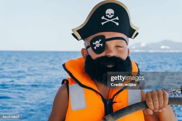 little boy in pirate costume steering yacht - miljko stock pictures, royalty-free photos & images