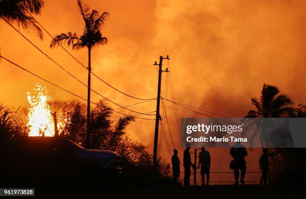 Lava erupts from a Kilauea volcano fissure as people gather on a residential street in Leilani Gardens, on Hawaii's Big Island, on May 23, 2018 in...