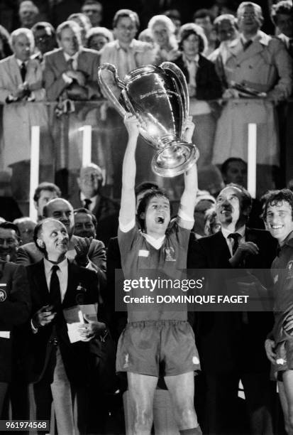 Liverpool's English defender and captain Phil Thompson raises the trophy as he celebrates winning the European Cup final football match between...