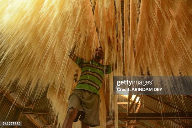 An Indian worker arranges strands of vermicelli noodles to dry inside of a factory during the Muslim holy fasting month of Ramadan on the outskirts...