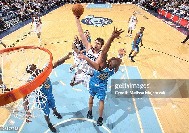 Mehmet Okur of the Utah Jazz shoots a layup against Emeka Okafor and David West of the New Orleans Hornets during the game at the EnergySolutions...