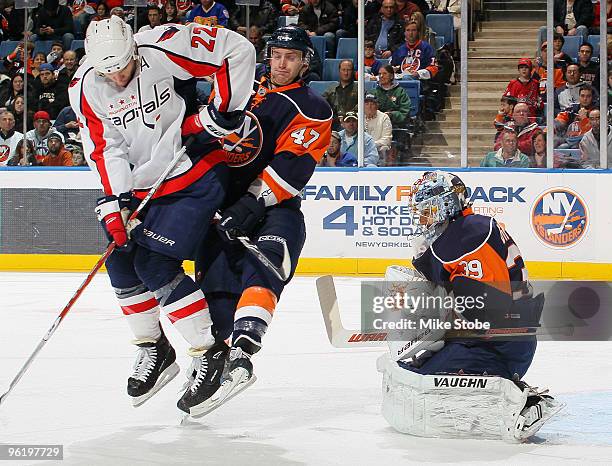 Mike Knuble of the Washington Capitals and Andrew MacDonald of the New York Islanders battle for position in front of Rick DiPietro as DiPietro makes...