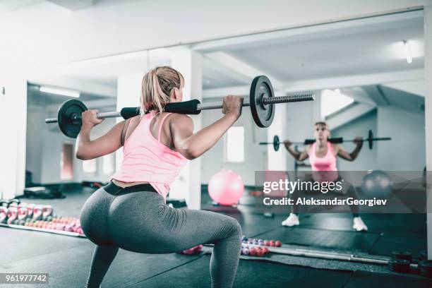 vrouwelijke atleet doen squats met gewichten in de sportschool - womens bottoms stockfoto's en -beelden