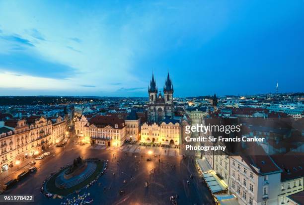 prague's old town square (stare mesto) with tyn cathedral gothic spires in the center, all illuminated at dusk in prague, czech republic - týnkerk stockfoto's en -beelden