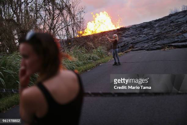 Resident Kathy Threlfall takes photos as local homeowner Chloe Child looks on as lava erupts and flows from a Kilauea volcano fissure in Leilani...
