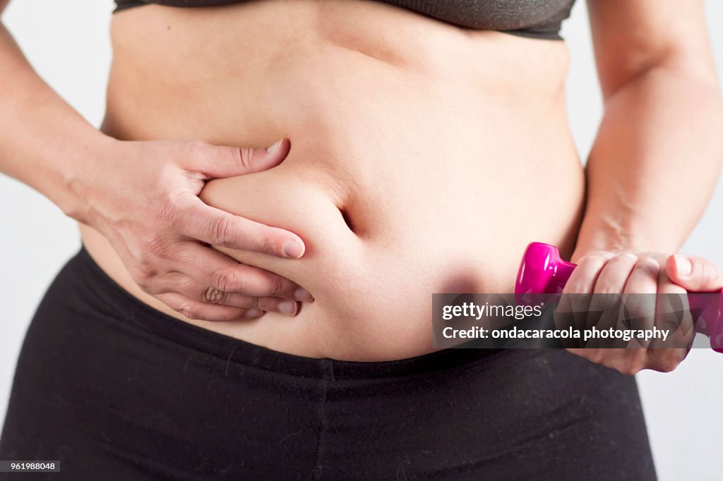 A woman's belly with overweight and dumbbells