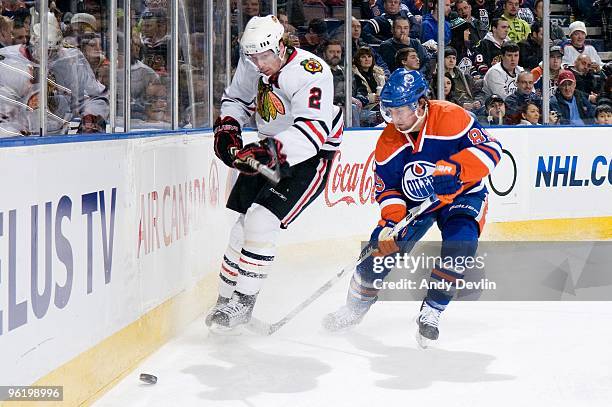 Duncan Keith of the Chicago Blackhawks clears the puck under pressure from Sam Gagner of the Edmonton Oilers at Rexall Place on January 26, 2010 in...