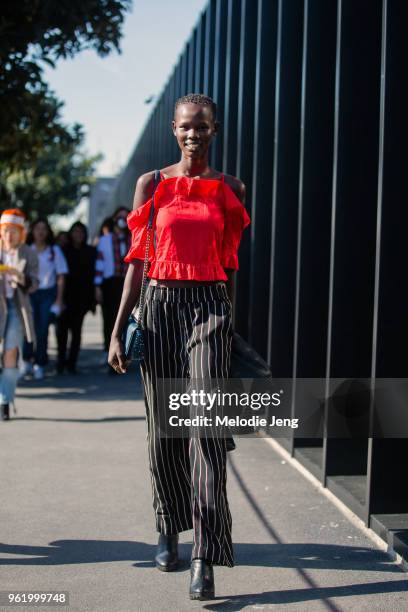 Model Shanelle Nyasiase wears a red ruffle tanktop, blac striped pants, and black boots after the Gucci show during Milan Fashion Week Spring/Summer...