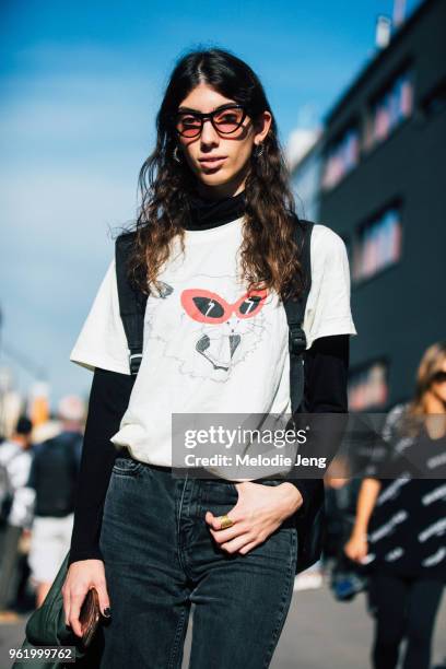 Turkish model Oyku Bastas wears pink retro style sunglasses, tshirt of a cat illustration with red sunglasses, and black jeans during Milan Fashion...