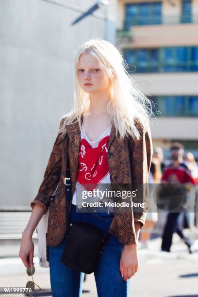 Model Unia Pakhomova wears an animal skin jacket, shirt with a heart, black bag, and jeans after the Gucci show during Milan Fashion Week...