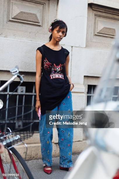 Model Londone Myers wears colorful printed headphones, a long sleeveless black sequin flying owl Tommy Hilfiger shirt, oversized Tommy Hilfiger jeans...