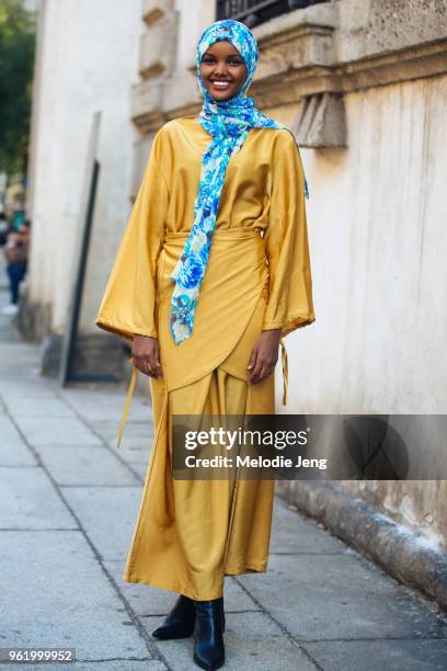 Model Halima Aden wears a blue floral head scarf, a yellow silk dress, and black boots after the Max Mara show during Milan Fashion Week...