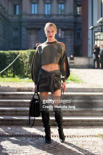 Model Hannah Ferguson wears a cropped green United States Marine Corps sweatshirt, a camouflage skirt, and knee high black boots after the Max Mara...