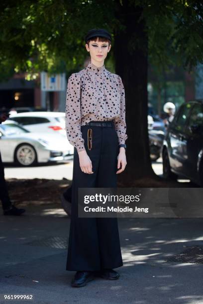 Model Gisele Fox wears a black newsboy cap, a light purple polkadot silk shirt, wide-legged black pants, and sunglasses on her belt after the Fendi...