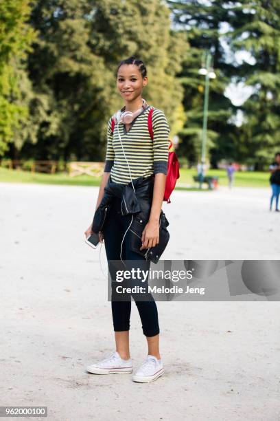 Model Lineisy Montero wears pink Beats headphones and wears a green striped shirt, leather jacket around her waist, black leggings, and white...