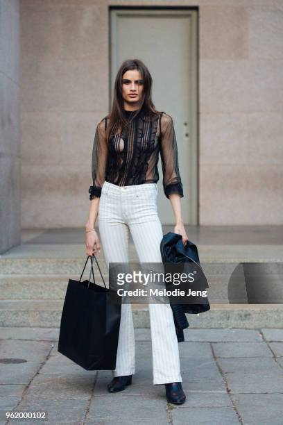 Model Linda Helena wears a lace black top, white striped pants after the Versace show during Milan Fashion Week Spring/Summer 2018 on September 22,...